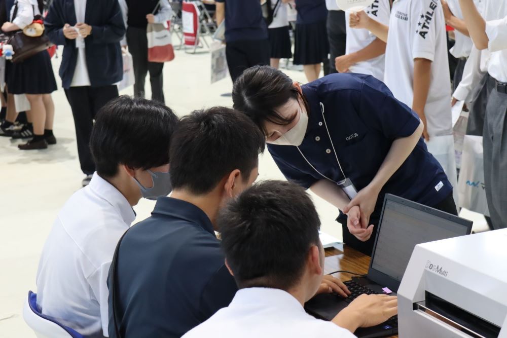 従業員が高校生へ点字入力の説明をしている写真